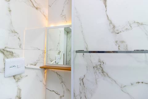 Banheiro moderno e bem iluminado em apartamento mobiliado para temporada – fotografia imobiliária em São Vicente.'