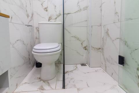 Banheiro moderno e bem iluminado em apartamento mobiliado para temporada – fotografia imobiliária em São Vicente.'