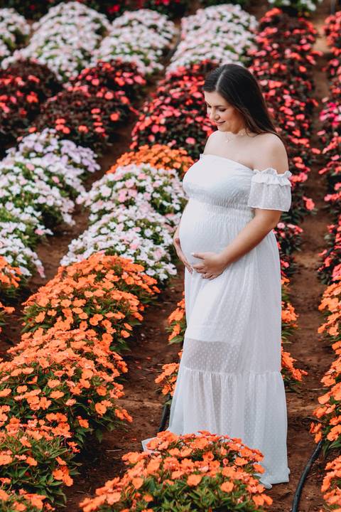 segurando barriga em meio plantação flores'
