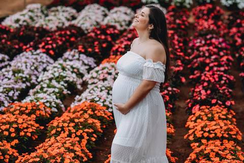 plantação de flores larange, branca e roxa com gestante ao meio'
