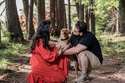 casal agachados com cachoro ao meio'