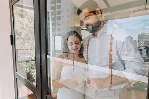 casal fazendo um brinde com reflexo na janela da cidade de sp
'