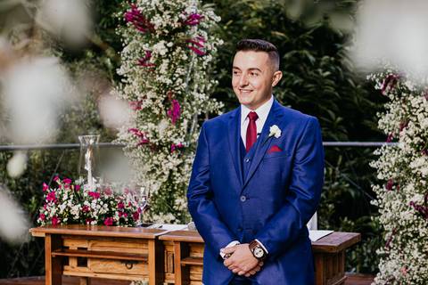 noivo no altar terno azul e gravata vermelha esperando a noiva'