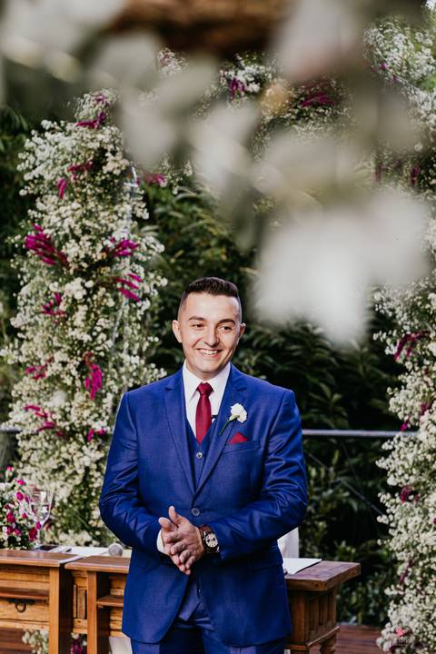 noivo no altar terno azul e gravata vermelha esperando a noiva'