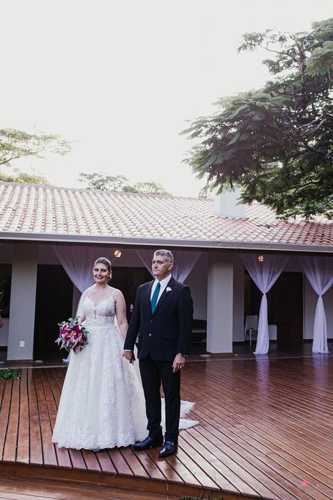 noiva e pai entrando no corredor noivo no altar terno azul e gravata vermelha esperando a noiva'