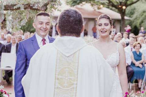 casal ao centro e padre no meio de costas'