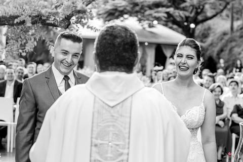 casal ao centro e padre no meio de costas'