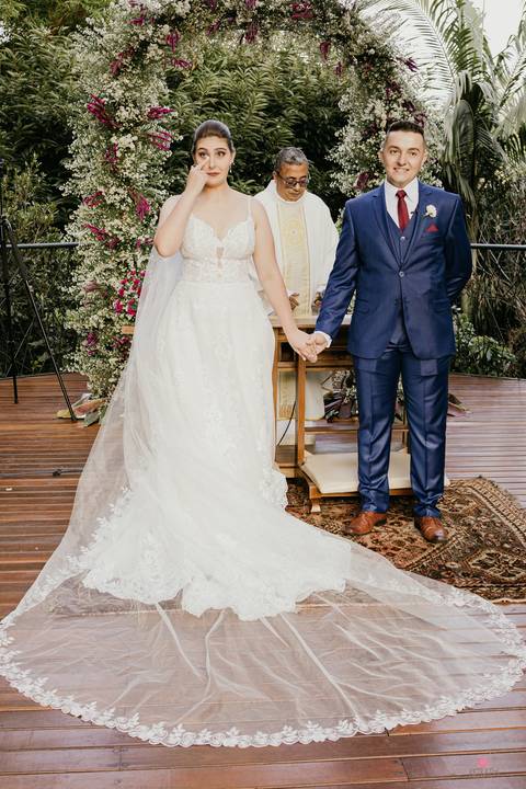 casal ao centro e padre no meio de costas'