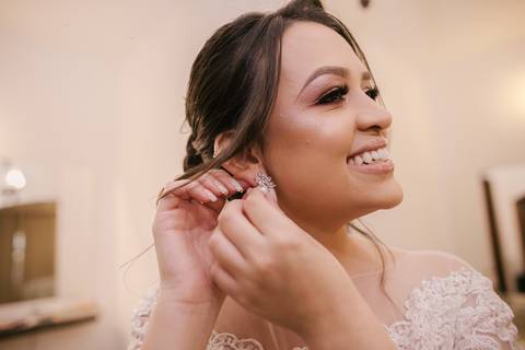 noiva colocando os brincos e sorrindo'