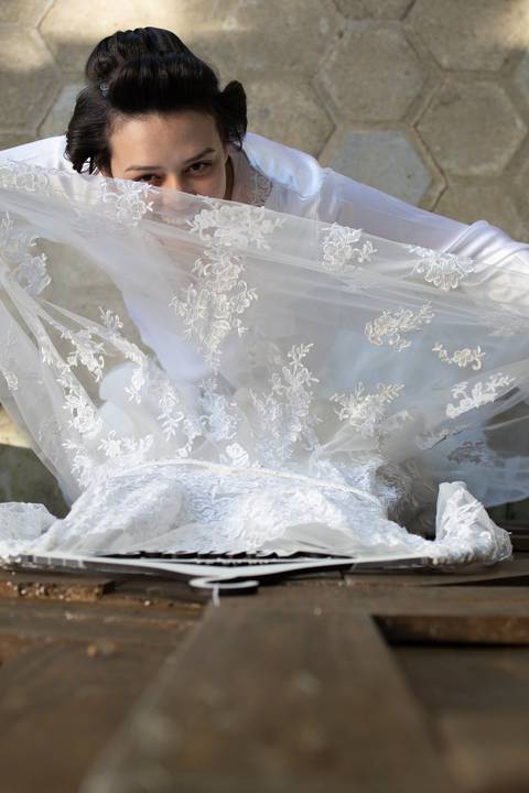 noiva vendo vestido de noiva pendurado numa porta rustica'