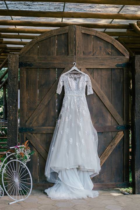vestido noiva pendurando numa porta rustica'