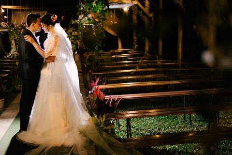 casal no local da cerimonia com bancos vazios'