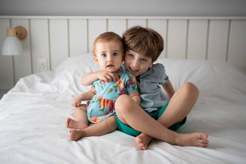 Bebê de 9 meses abraçada com o irmão mais velho; crianças sentadas na cama; Joao-Francisco-Fotografia; Familia; Niteroi; Rio de Janeiro; Acompanhamento; life-style;'