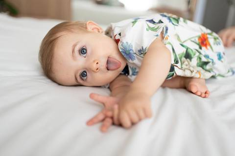 Bebê deitada de lado na cama com a língua pra fora; Joao-Francisco-Fotografia; Familia; Niteroi; Rio de Janeiro; Acompanhamento; life-style;'