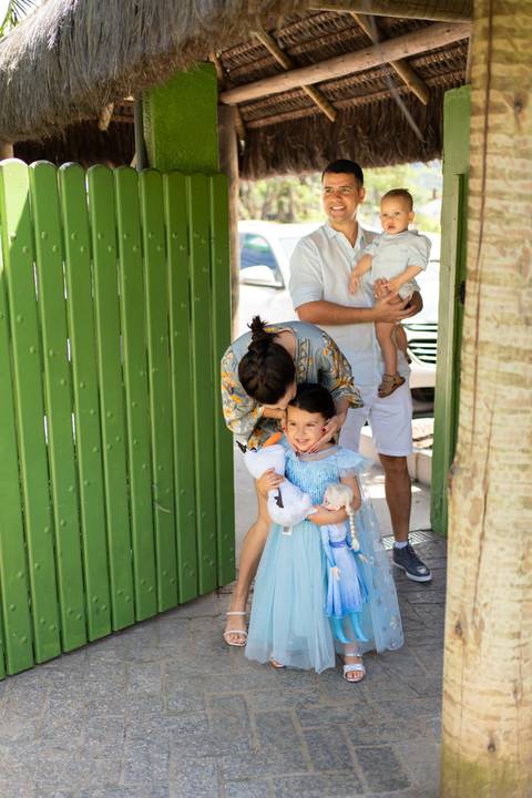 Festa infantil de aniversário de menina de 4 anos com o tema Frozen; princesa Elsa; princesa Anna; vestido azul; Olaf ; família chegado na festa; mae beijando rosto da filha;'