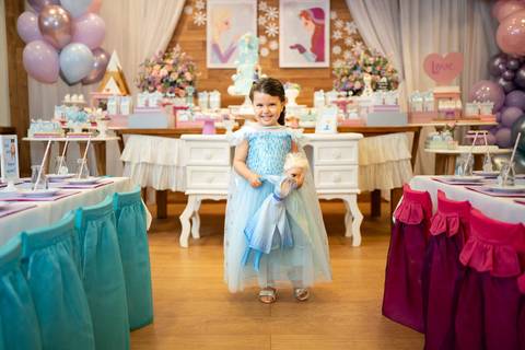 Festa infantil de aniversário de menina de 4 anos com o tema Frozen; princesa Elsa; princesa Anna; retrato da menina de vestido azul segurando boneca Elsa enquanto sorri pra câmera ; quintal de contos; niteroi; Rio de Janeiro; fotografo de familia'