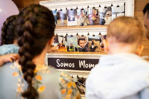 Festa infantil de aniversário de menina de 4 anos com o tema Frozen; princesa Elsa; princesa Anna; família de costas desfocados observando quadro de fotos com memórias de viagens; quintal de contos; niteroi; Rio de Janeiro; fotografo de familia'