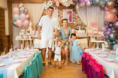 Festa infantil de aniversário de menina de 4 anos com o tema Frozen; princesa Elsa; princesa Anna; vestido azul; retrato da família; pais de mãos dadas com os filhos sorrindo para a foto; quintal de contos; niteroi; Rio de Janeiro; fotografo de familia'