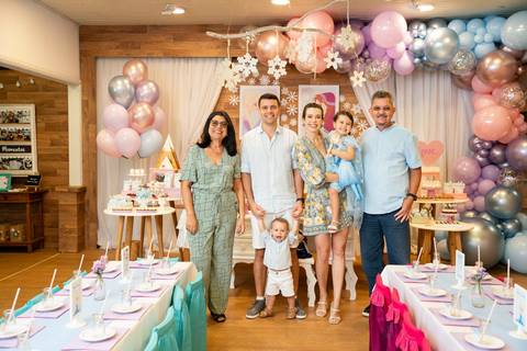 Festa infantil de aniversário de menina de 4 anos com o tema Frozen; princesa Elsa; princesa Anna; vestido azul; retrato da família em pé em frente a mesa do bolo, com os pais e avós das crianças; quintal de contos; niteroi; Rio de Janeiro; fotografo de f'