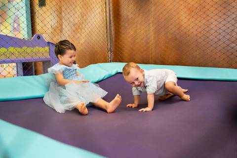 Festa infantil de aniversário de menina de 4 anos com o tema Frozen; princesa Elsa; princesa Anna; menina de vestido azul com o irmão pulando na cama elástica;'