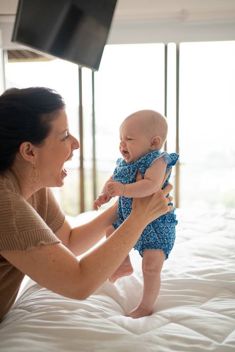 Ensaio familia; Acompanhamento; Bebe; Menina; 3 meses; em casa; Life Style; Joao-Francisco; Fotografia; Sessão; Fotos; mãe segurando bebê em pé sobre a cama; roupa azul; Joao-Francisco-Fotografia; Familia; Niteroi; Rio de Janeiro; Acompanhamento;'