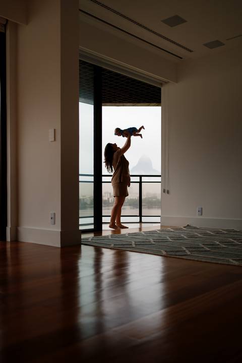 Ensaio familia; Acompanhamento; Bebe; Menina; 3 meses; em casa; Life Style; Joao-Francisco; Fotografia; Sessão; Fotos; Mãe levantando bebê; morro dois irmão ao fundo; Silhueta na varanda; mãe erguendo a bebê pro alto;'