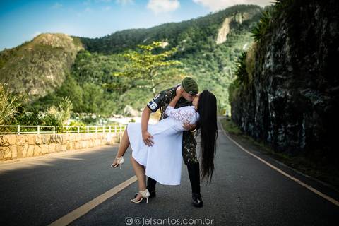 noivo militar fardado no prewedding e noiva de vestido branco relendo a fotografia da enfermeira'