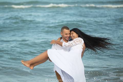 noiva no colo do noivo enquanto os cabelos da noiva voam com o mar de grumari ao fundo, fotografados pelo fotógrafo de casamentos jef santos'
