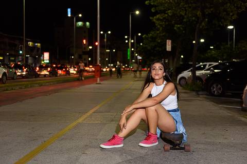 menina sentada no skate em ensaio externo a noite na orla de camburi vitoria'
