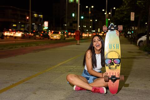 menina sorrindo segurando skate'