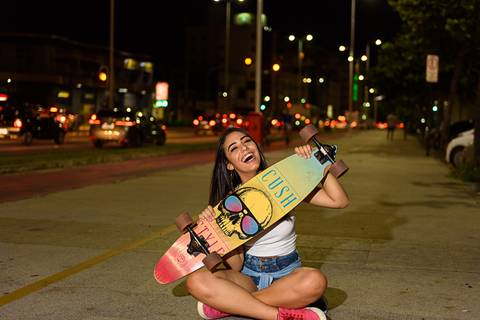 menina posando com skate na mão'