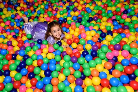 menina pulando na piscina de bolinhas coloridas'