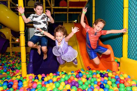 menina pulando na piscina de bolinhas com amigos'