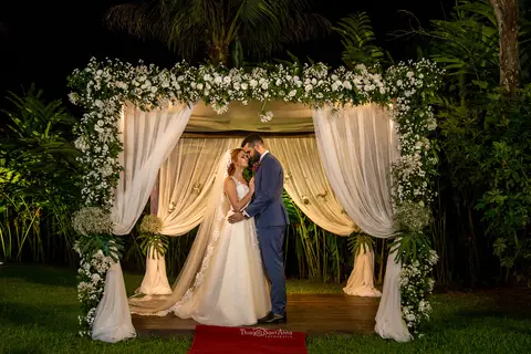 Fotografia de noivos clássica em casamento rústico embaixo de gazebo florido com cortina branca'