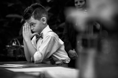 Foto em preto e branco do pagem durante a oração na cerimônia do casamento na Vila Caniza. Fotógrafo de casamento no Rio de Janeiro por Thiago Sant' Anna Fotografia'