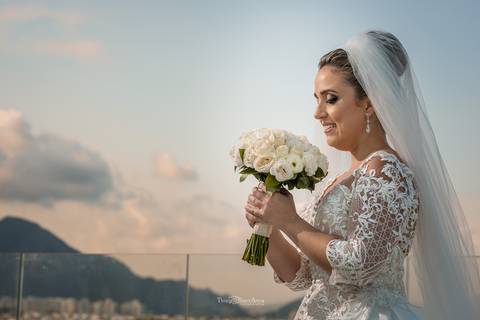Noiva olhando o Buquê, com céu de fundo'