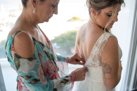 mãe fecha o vestido da noiva '