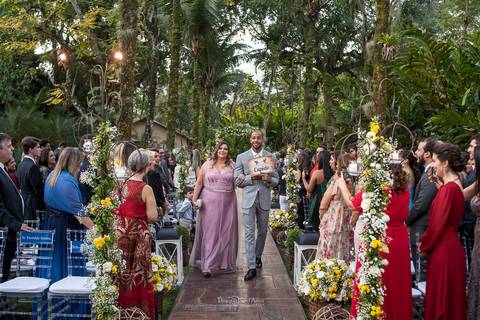 entrada de padrinhos convidados observam decoração vegetal flores brancas e amarelas '