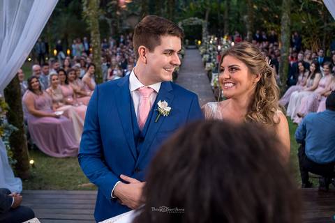 noivos no altar se olhando madrinhas e convidados ao fundo decoração natural '