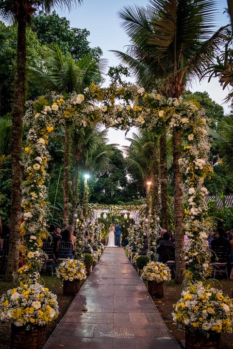 decoração natural coqueiros flores brancas e amarelas noivos ao fundo '