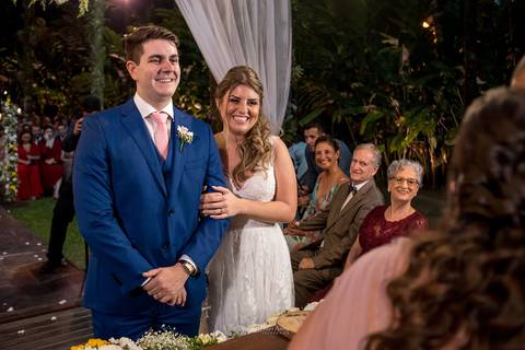 noivos sorriem no altar familiares observam '