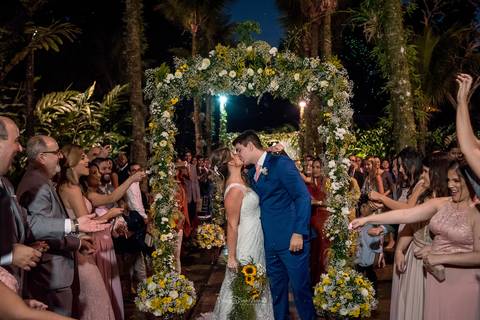 beijo dos noivos padrinhos jogam arroz decoração vegetal flores brancas e amarelas '