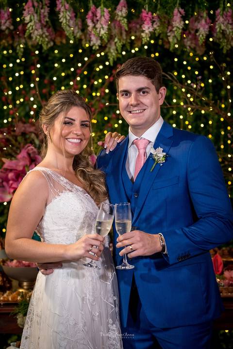 noivos brindam sorrindo decoração luzes e flores cor de rosa '