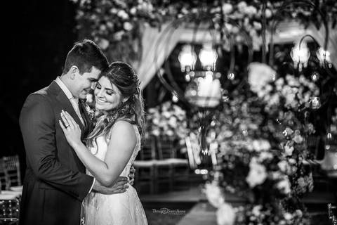 noivos se abraçam decoração altar ao fundo flores amarelas e branca preto e branco'