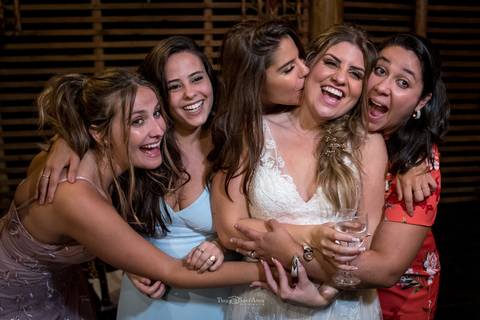 noiva sorri recebendo abraço de convidadas '