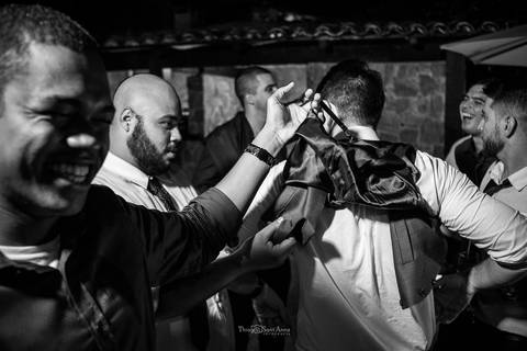 convidados riem e brincam com a roupa do noivo '