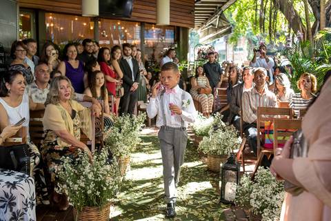entrada do pajem assoprando bolas de sabão decoração flores brancas convidados ao fundo'