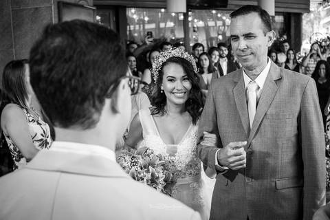 a noiva e seu pai chegam até o noivo convidados ao fundo preto e branco'