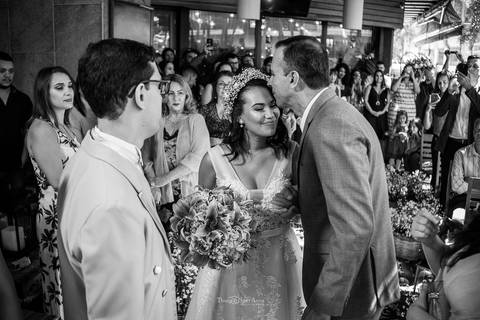 o pai da noiva beija sua testa convidados ao fundo preto e branco'