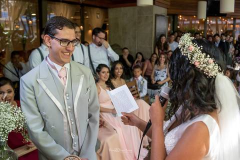 noiva lê seus votos de casamento noivo sorri padrinhos observam sorrindo'
